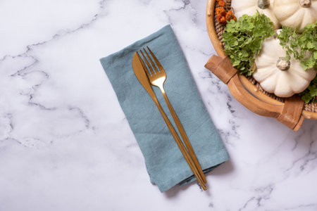 Autumn flat lay with cutlery on napkin and decorative pumpkins on marble background top view.の写真素材