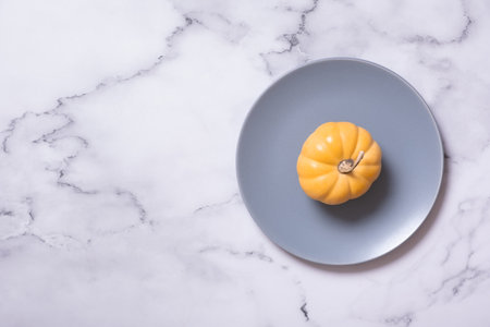Orange pumpkin on a blue plate from above. Minimalist concept of the autumn menu.の写真素材