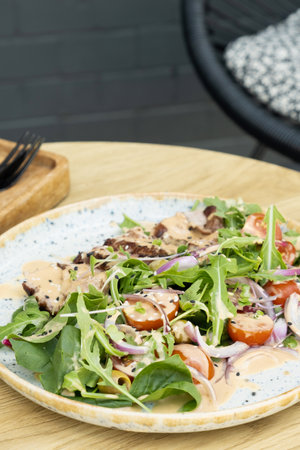 A plate with meat salad of veal with arugula, tomatoes under nut sauce close up.の写真素材