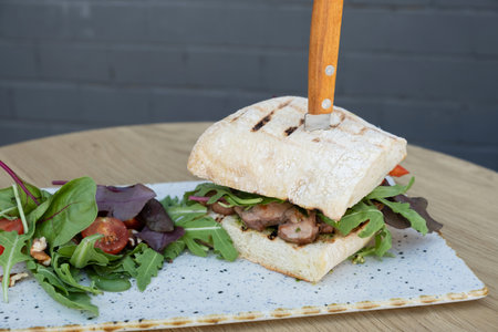 Burger with meat and vegetables on wooden table.の写真素材