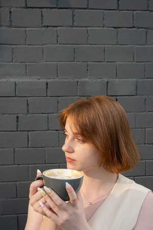 Beautiful young woman with freckles drinks coffee latte..の写真素材