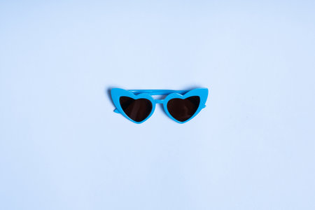 Children's sunglasses in the shape of a heart on a blue background, top view.の写真素材