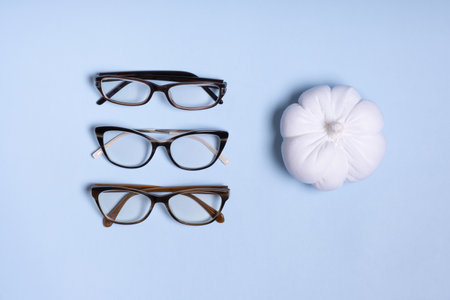 Glasses for vision on a blue background next to a pumpkin. Optical store, vision test, stylish glasses concept.の写真素材