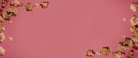 Golden fall autumn leaves of different shapes on pink background. Autumn concept, fall background. Minimal floral design, autumn leaf frame with copy space. Autumn creative composition. Banner.の写真素材