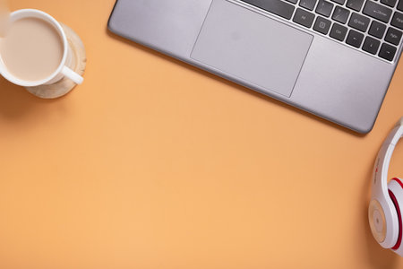 Flat lay office table desk. Workspace with blank orange beckground and coffee cup, headphones top viewの写真素材
