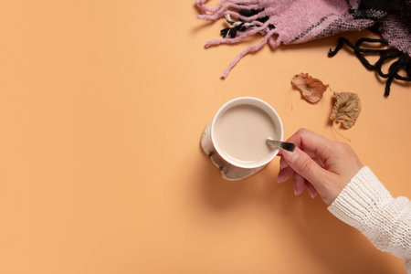 Female hand in sweater holding cup of cocoa on colored background, top view with copy space.の写真素材
