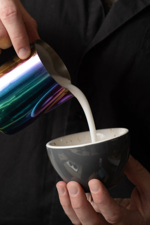 The barista makes a drawing on the coffee. Latte art processing close up.の写真素材