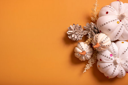 White decorative hand made pumpkins with shiny stones and pine cones on colored background top view. Thanksgiving day conceptの写真素材