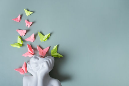 A figurine of a head with butterflies on a colored background. Mental health concept. Copy space.の写真素材