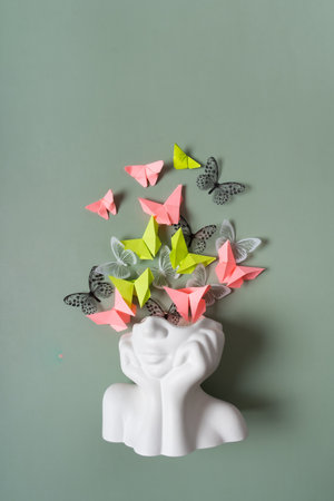 A figurine of a head with butterflies on a colored background. Mental health concept.の写真素材