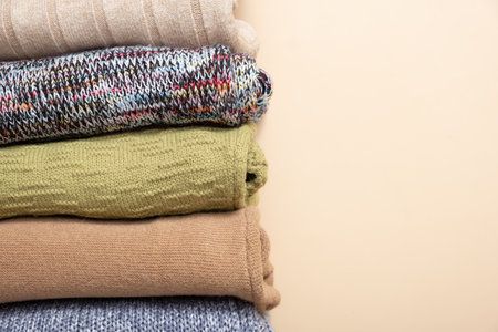 A stack of cozy knitted sweaters on beige background. Warm concept.の写真素材
