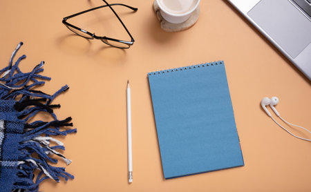 Office table desk with set of colorful supplies, blank blue paper note pad, plaid, cup, pen, pc on colored background. Top view and copy space for text.の写真素材