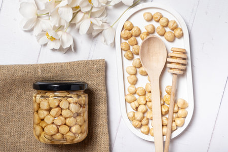 Glass jar with honey and nuts on beige background. Hazelnuts in honey. Top view.の写真素材