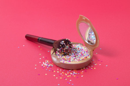 Makeup powder and cosmetic brush with glitter stars on red background.の写真素材
