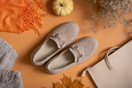 Autumn casual shoes flat lay. Suede shoes and bag with autumn leaves and pumpkin on orange background top view.の写真素材