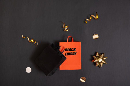Black friday text, sale concept. Red and black paper shopping bags with decorations on black backgroundの写真素材
