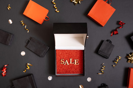 Black friday sale concept. Sale text in black gift box and shopping bags with festive decorations on...
