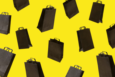 Pattern from black sale shopping bags are flying on yellow background. Black Friday creative idea conceptの写真素材