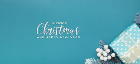 Merry Cristmas insription greeting banner with flat lay Christmas gift, berries and pine turquoise backgroundの写真素材