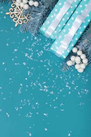 Merry Christmas greeting card on a background of gifts, berry and snow flat lay on a turquoise backdrop, vertical format with copy spaceの写真素材