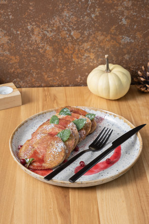 A plate of pumpkin pancakes with cutlery on wooden background top view, flat lay.の写真素材
