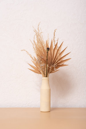 Bouquet of beige dried flowers and paper palms in a beige vase on white background.の写真素材