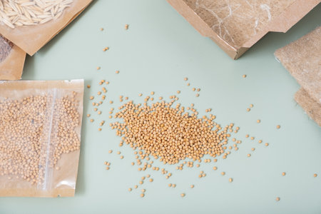 Seeds mustard in bags close-up for growth microgreens on green background top view, flat lay.