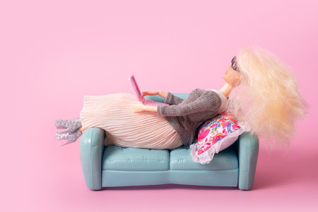 Doll with laptop on sofa. Working or relax at home, freelance creative conceptの写真素材