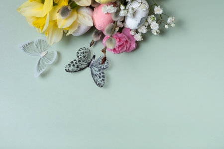 Butterflies and yellow daffodils, easter eggs and willows twigs on green background with copy space.の写真素材