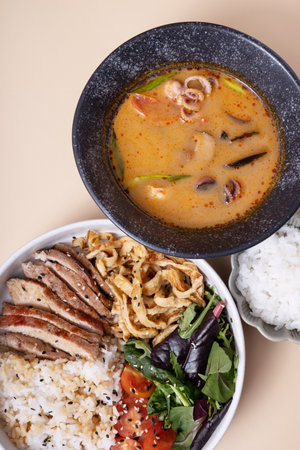 Bowl with rice, veal and vegetables and tom yam soup angle viewの写真素材
