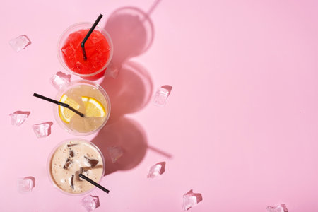 Three takeaway glasses of summer drinks with ice. Lemonade on colored background.の写真素材