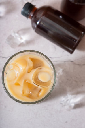 Cold brew coffee with milk and ice and cold brew coffee in bottles top view