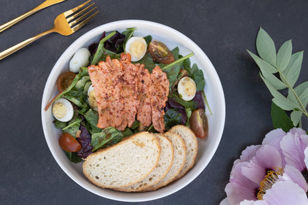 Salmon and lettuce salad with tomatoes and quail eggs and toasts top view.の写真素材