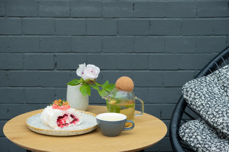 Cup of tea and teapot with meringue roll on the table. Sweet food teatime concept.の写真素材