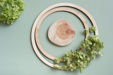 Wooden frame with saw pedestal top view decorated with dry hydrangea flowers on pastel green colored background.の写真素材