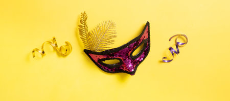 Festive face mask and shiny spirals for carnival celebration on colored backgroundの写真素材