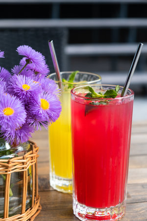 Two glasses with drinks with ice and mint on wooden tableの写真素材