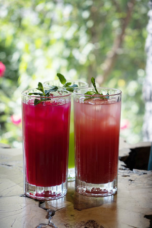 Colored summer lemonades with ice and mint on wooden cafe tableの写真素材