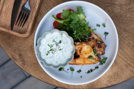 Delicious fried chicken wings with yogurt sauce and greens top viewの写真素材