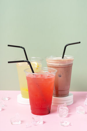 Three takeaway cups of summer drinks with ice. Lemonade on colored background.の写真素材