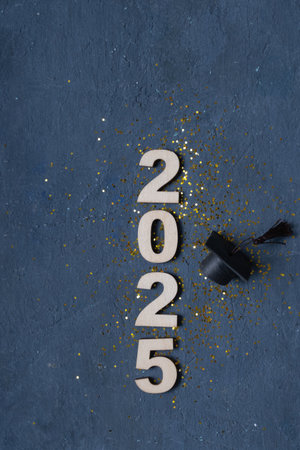 Graduation cap on wooden number 2025 on dark background. Class of 2025 concept