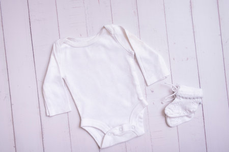 White baby bodysuit mockup for logo, text or design on wooden background top view.の写真素材