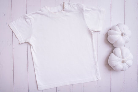 White children's t-shirt mockup for logo, text or design on wooden background with pumpkins top view.の写真素材