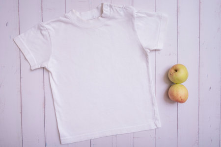 White children's t-shirt mockup for logo, text or design on wooden background top view.の写真素材