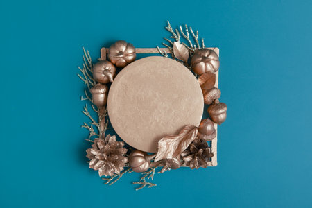 Still life of golden acorns, cones, leaves and pumpkins on a turquoise background with a pedestal. Minimalistic autumn concept with copy spaceの写真素材