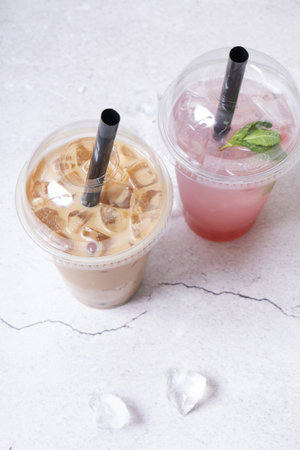 Two vibrant bubble tea drinks showcase enticing flavors, one creamy and pale with ice, the other a...