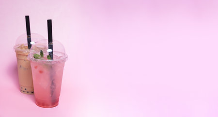 Refreshing bubble tea drinks are showcased in clear cups with black straws, featuring a mix of colors. Mint leaves and tapioca pearls add to the appealing presentation.の写真素材