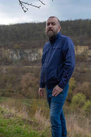 Man stands on a hillside overlooking a scenic valley during a cloudy day in natureの写真素材