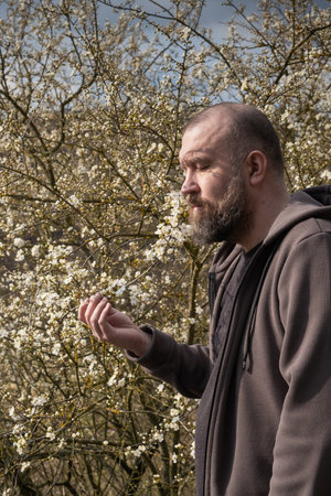 Man enjoying nature while standing among blooming flowers in early spring sunlightの写真素材