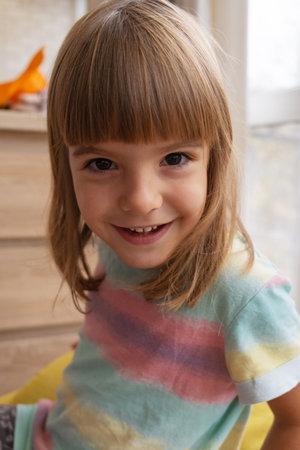 Smiling girl with brown hair sits comfortably in a cozy living room